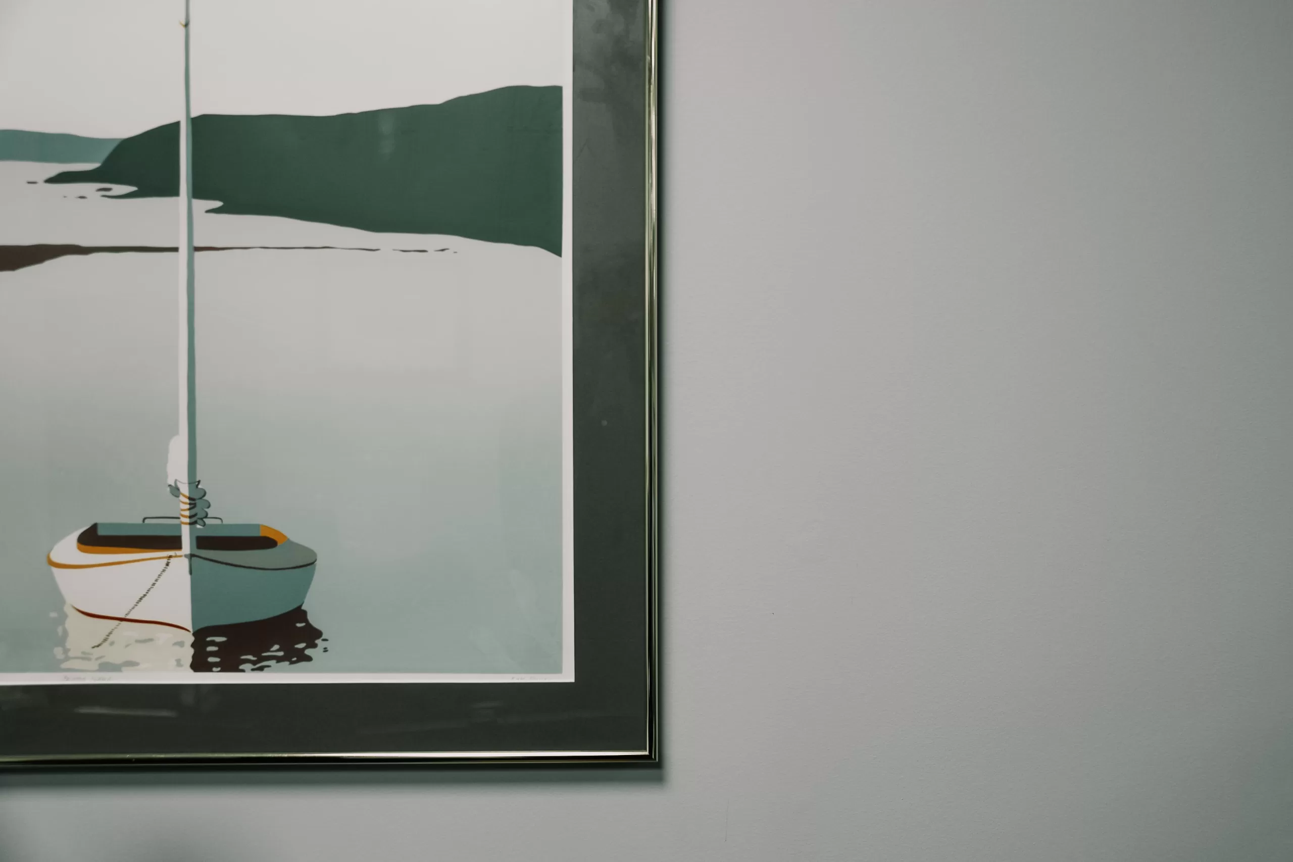 Art print of a boat on calm water, hanging on a light gray wall.