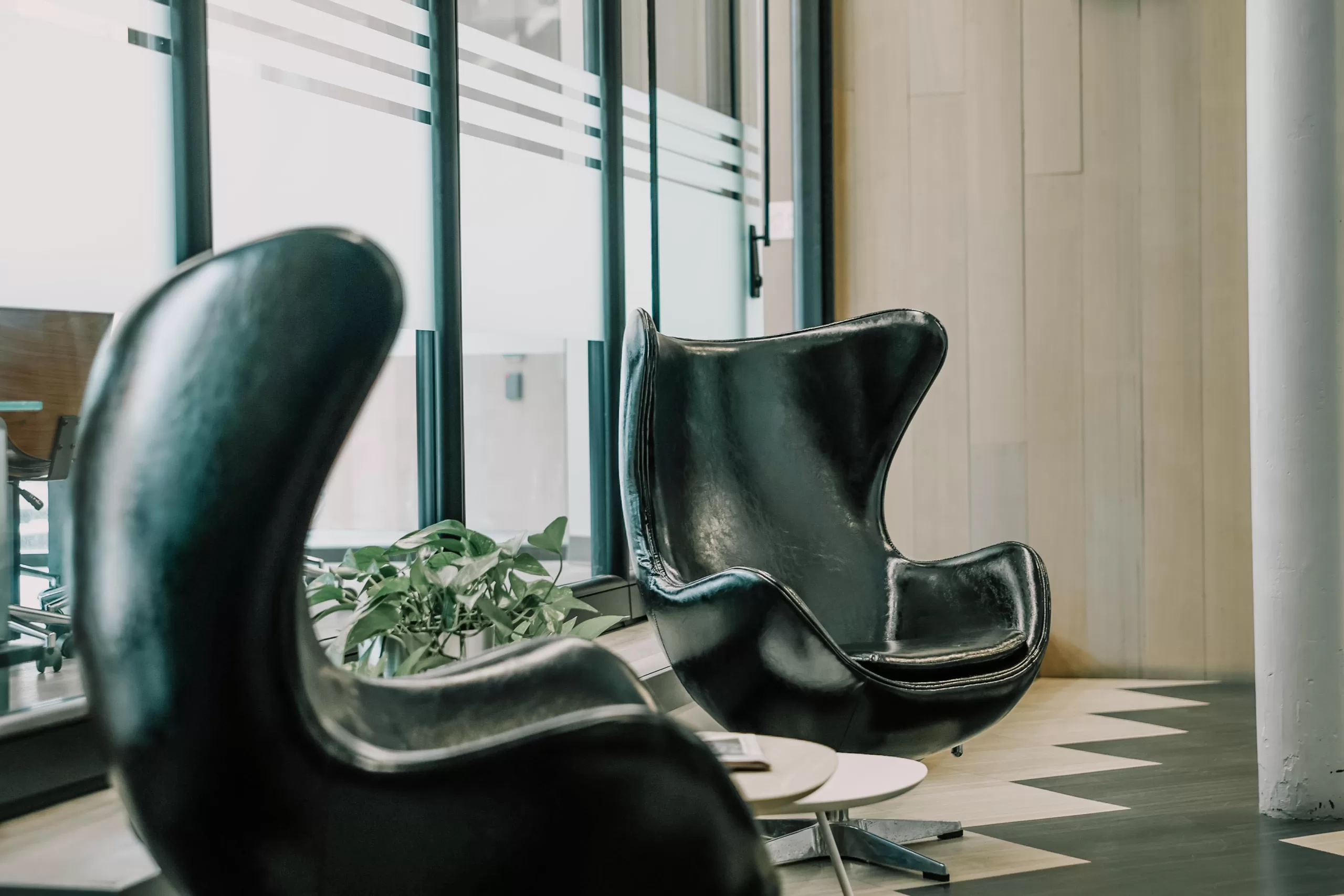Two modern black chairs in a stylish office with large windows.